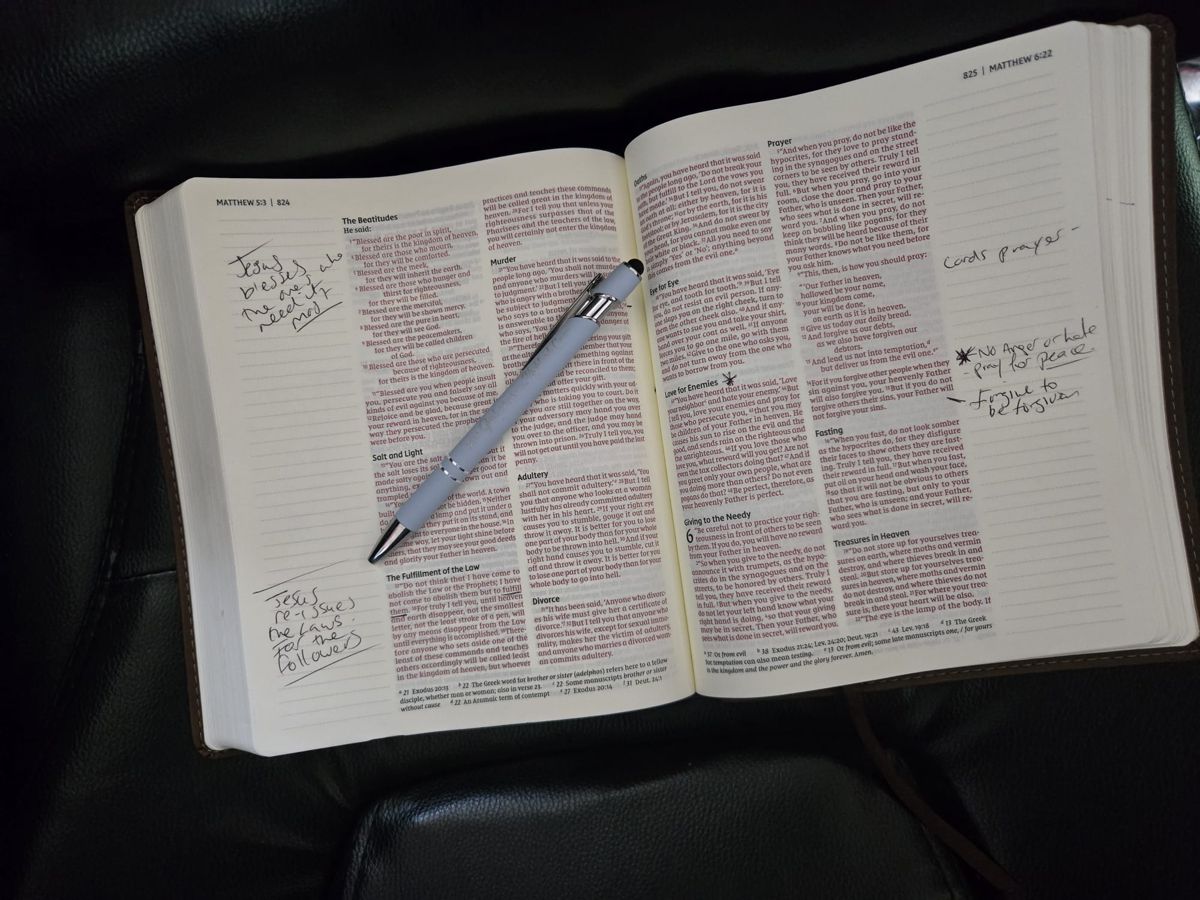 An open Bible at Matthew, with handwritten study notes and a pen