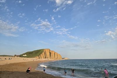 Children playing in the sea below cliffs on an evening beach