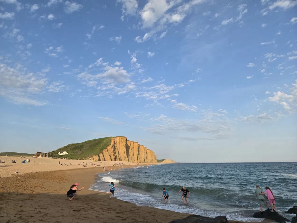 Children playing in the sea below cliffs on an evening beach