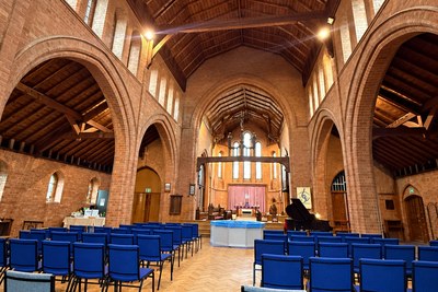 The empty nave of St Philip the Deacon church, Upper Stratton, with rows of blue chairs facing the altar